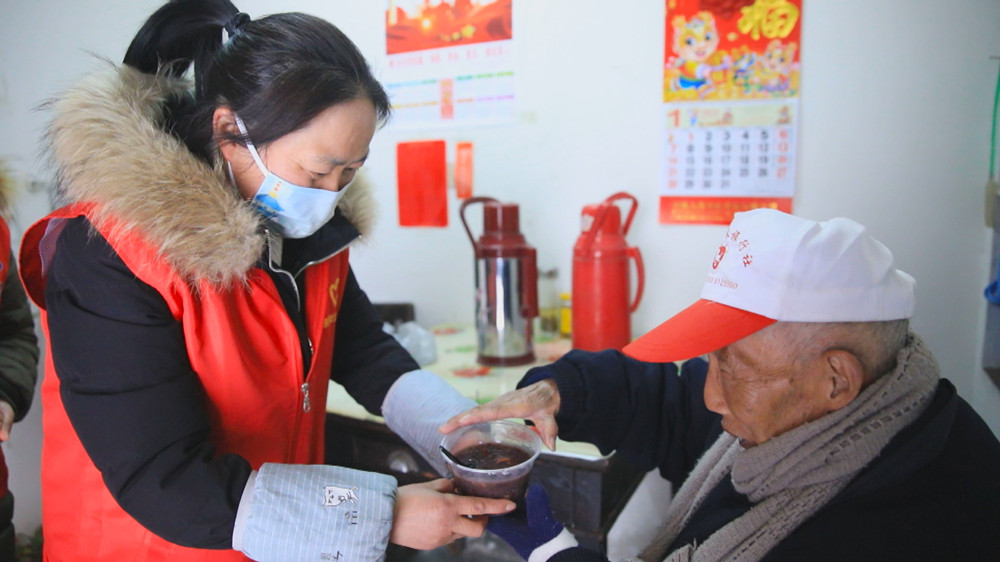 圖為社區(qū)志愿者上門送粥給行動(dòng)不便的居民.jpg