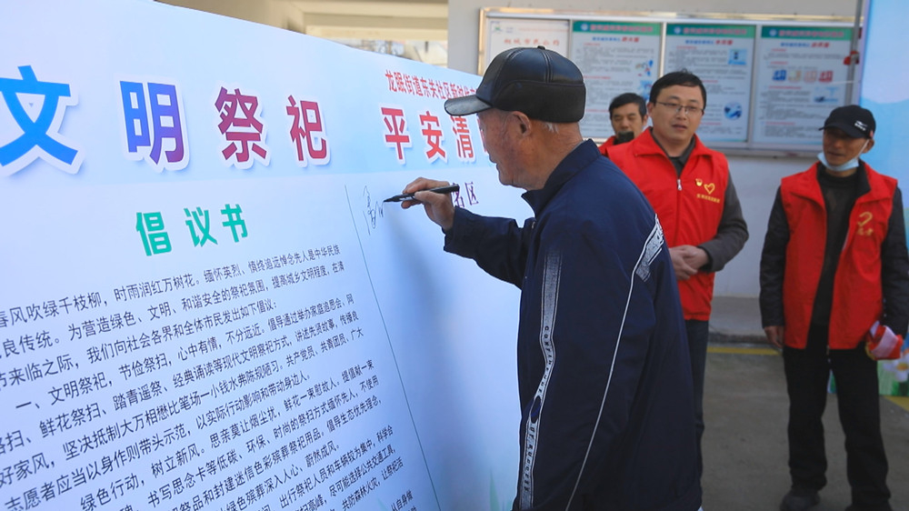 圖為社區(qū)居民正在文明祭祀倡議書上簽字.jpg