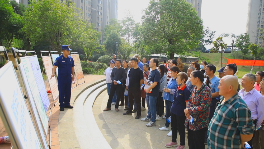 圖為消防員正在結(jié)合展板為小區(qū)居民講解防災減災自救知識.jpg